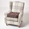 A brown seat cushion is placed on a plaid armchair. Náhled obrázku produktu