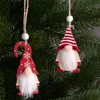 Two wooden gnome ornaments hang from a Christmas tree. Náhled obrázku produktu