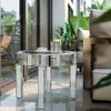 A mirrored round coffee table with a cup and a decorative container on it, placed on a balcony with plants and furniture. Anteprima dell’immagine prodotto