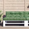 A green pallet cushion with a leaf pattern is placed on a white pallet sofa.