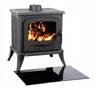 A black cast iron wood-burning stove with a glass door showing burning logs, placed on a black glass hearth plate. Náhled obrázku produktu