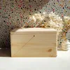 A light wood box with a lid sits on a white surface, with a speckled wall in the background and dried flowers in a vase to the right. Náhľad obrázku produktu