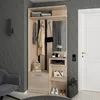 A hallway furniture set with a mirror, coat hooks, shelves, and a drawer, next to a door and a chair. Náhled obrázku produktu