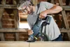 A man is using a reciprocating saw in a wooden structure. Voir les images du produit