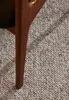 A close-up view of a wooden furniture leg resting on a textured carpet. Voir les images du produit