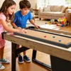 Two children are playing a shuffleboard and curling game on a table in a living room. Produktbild-Vorschau