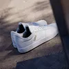 A pair of white Adidas sneakers are placed on a textured concrete surface, with shadows cast by an unseen object. Produktbild-Vorschau