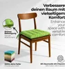 A green seat cushion on a wooden chair, with text overlays and a stack of colorful cushions in the corner. Produktbild-Vorschau