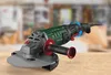 An angle grinder is placed on a wooden surface with a blurred workshop background. Produktbild-Vorschau