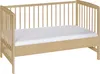 A light-colored wooden crib with a white mattress is shown against a white background. Produktbild-Vorschau