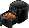 A black air fryer with a whole roasted chicken and vegetables inside the basket. Produktbild-Vorschau