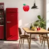 A kitchen scene with a red refrigerator, a dining table with chairs, and a wall clock shaped like an apple. Produktbild-Vorschau