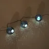 A string of three solar-powered decorative lights with perforated spherical shades, casting patterned light onto a wall. Produktbild-Vorschau