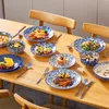 A table set with multiple plates of food and tableware, arranged on a wooden table. Produktbild-Vorschau