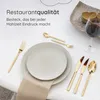 A table setting with gold cutlery, plates, and a glass of red wine. Produktbild-Vorschau