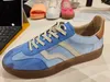 A blue Gant sneaker is displayed on a table, with a laptop and other shoes in the background. Produktbild-Vorschau