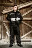 A man in workwear stands in front of a wooden door. Produktbild-Vorschau