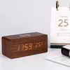 A wooden digital clock with a wireless charging pad on top, displaying the time and temperature, sits on a white surface next to a desk calendar. Produktbild-Vorschau