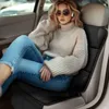 A woman is sitting in the passenger seat of a car, wearing a sweater and jeans. Anteprima dell’immagine prodotto