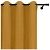 A close-up view of a mustard yellow curtain with grommets hanging from a black curtain rod. Náhled obrázku produktu