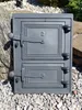 A cast iron oven door with two compartments, placed on gravel with rocks and greenery in the background. Náhľad obrázku produktu