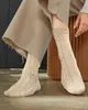 A person's legs wearing beige socks and a beige skirt. Produktbild-Vorschau