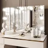 A vanity table with a mirror, makeup, and decorative items. Produktbild-Vorschau
