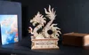 A wooden dragon model sits on a shelf next to a book and a wooden box. Anteprima dell’immagine prodotto