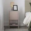 A bedside table with a lamp, e-reader, and phone.