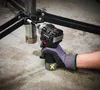 A person wearing a glove is using a cordless impact wrench to tighten a bolt on a metal stand. Produktbild-Vorschau