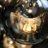 A close-up shot of a glass pendant light fixture, showing the intricate details of the light bulb and glass shade. Produktbild-Vorschau