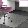 An office chair on a transparent floor mat placed on a carpeted floor, next to a desk. Produktbild-Vorschau