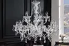 A crystal chandelier hangs in a room with a dark wall and a window view of a city at night. Náhled obrázku produktu