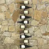 A wine rack mounted on a stone wall, holding several bottles of wine. Náhľad obrázku produktu