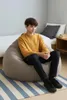 A young person sits on a large beanbag chair in a bedroom setting. Voir les images du produit