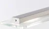 A close-up shot of a silver bar-shaped light fixture with a small button on one end, resting on a clear glass surface. Produktbild-Vorschau