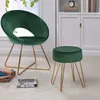 A dark green velvet chair and ottoman with gold metal legs are shown in a room with a window and a bookshelf. Produktbild-Vorschau