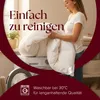 A woman is holding a white duvet in front of a washing machine, suggesting it is easy to clean. Produktbild-Vorschau