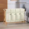 A beige laundry basket with four compartments and a bamboo frame, placed in a bedroom setting. Anteprima dell’immagine prodotto