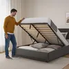A man is lifting the mattress of a bed to reveal storage space underneath. Produktbild-Vorschau