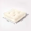 A cream-colored square cushion with tufted detailing is shown against a plain background, with dimensions indicated by arrows and text. Náhled obrázku produktu