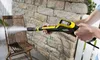 A person is using a Kärcher high-pressure gun to clean a wooden chair. Náhled obrázku produktu