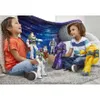 Two children are playing with Buzz Lightyear action figures in a room with a space-themed blanket. Produktbild-Vorschau