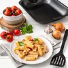 A black baking dish is shown in the background, with a plate of pasta in the foreground, surrounded by ingredients like tomatoes, onions, garlic, and basil. Anteprima dell’immagine prodotto