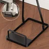 A close-up view of the base of a black metal vacuum cleaner stand, showing its sturdy construction and a small platform with a handle. The background is a wooden floor and a white wall. A circular inset highlights the vacuum cleaner head resting on a charg Produktbild-Vorschau