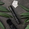 A black monocular telescope with "National Geographic" branding is laid out on a dark, textured surface, surrounded by green leaves. A cleaning cloth and a black carrying case are also present. Produktbild-Vorschau