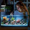 A woman is cleaning a saltwater aquarium with a gravel vacuum. Anteprima dell’immagine prodotto