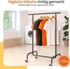 A clothing rack with t-shirts on hangers in front of a washing machine and a window. Produktbild-Vorschau