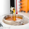 Honey being extracted from a honey extractor into a sieve and bucket. Produktbild-Vorschau