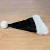 A black Santa hat with white trim and a white pom-pom lies on a wooden surface. Produktbild-Vorschau